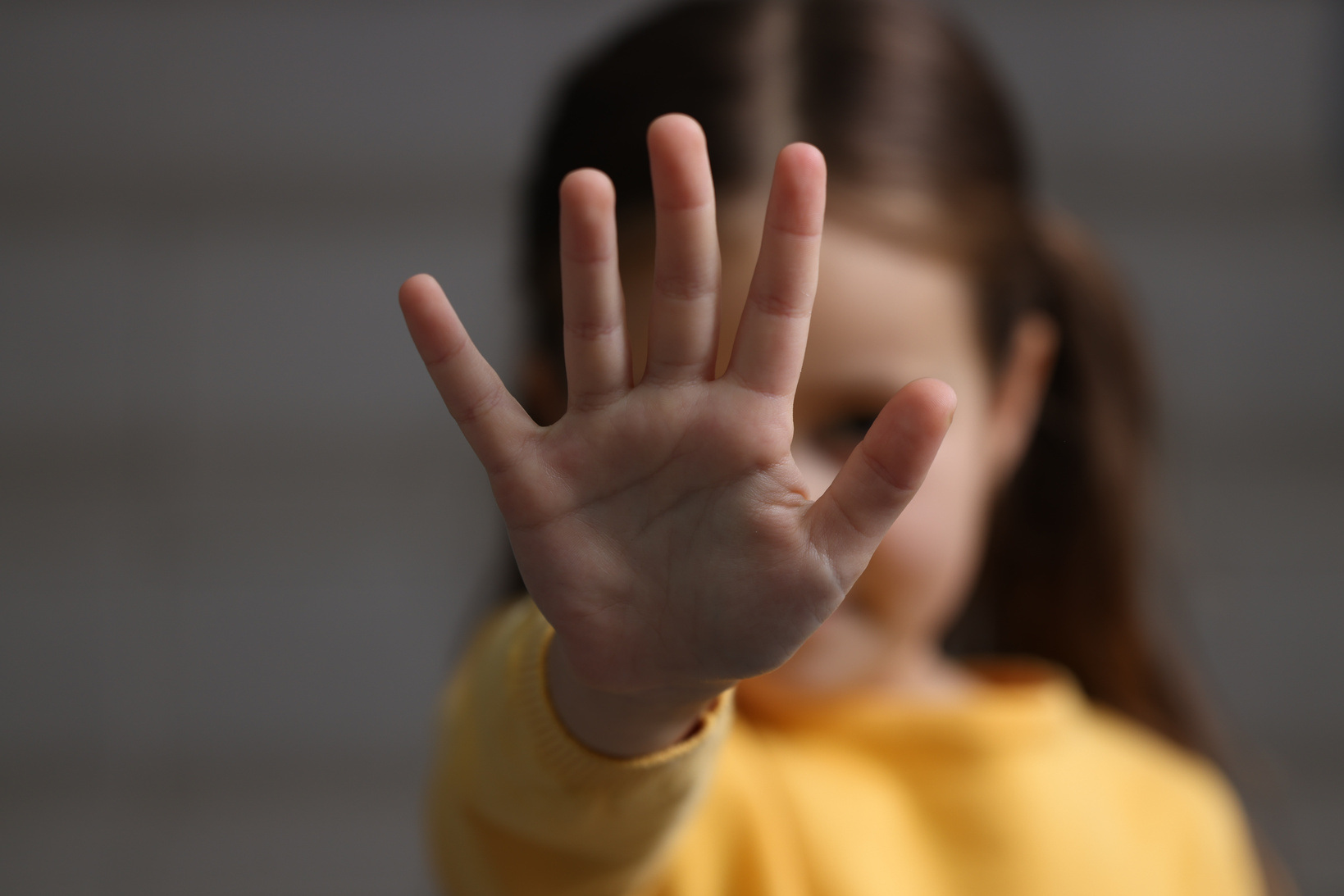 Child Abuse. Little Girl Doing Stop Gesture on Gray Background, Selective Focus