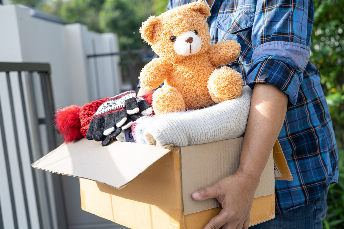 Holding clothing donation box with used clothes and doll at